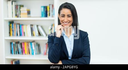 Graziosa businesswoman latino-americana matura con blazer all'ufficio dell'azienda Foto Stock