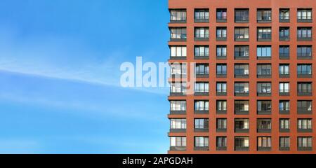 La moderna facciata in mattoni di un alto edificio contro il cielo blu Foto Stock