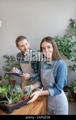 Donna e un uomo che piantano succulenti in pentole Foto Stock