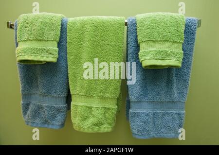 Asciugamani colorati sulla stanghetta sulla parete verde sotto le luci Foto Stock