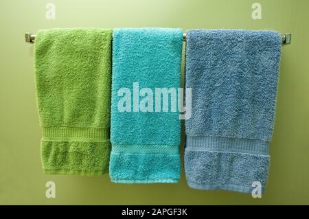 Asciugamani colorati sulla stanghetta sulla parete verde sotto le luci Foto Stock