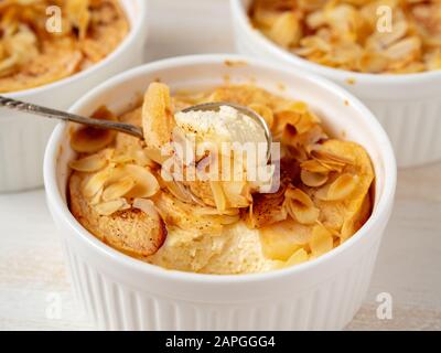 Cheesecake su tavolo di legno bianco in cucina. Delicato dessert al curdo con mele, fiocchi di mandorle Foto Stock