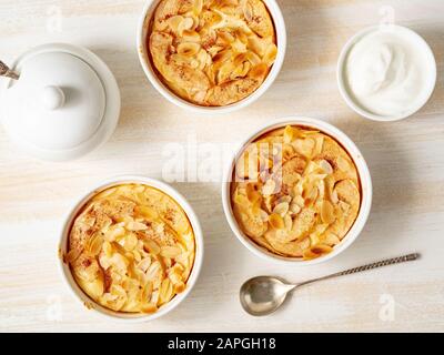 Cheesecake su tavolo di legno bianco in cucina. Delicato dessert al curdo con mele, fiocchi di mandorle Foto Stock