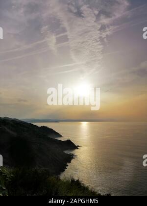 Immagine verticale di un affascinante tramonto che si riflette nell'oceano nella località turistica di San Sebastian, in Spagna Foto Stock