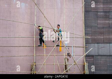 Hong Kong, novembre 2019: Lavoratori in cantiere che costruiscono impalcature di bambù sulla facciata della casa a Hong Kong Foto Stock