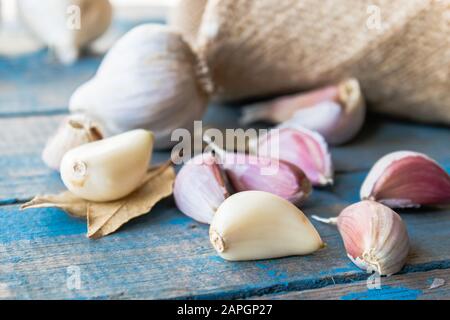 Spicchi d'aglio e bulbi d'aglio sulle vecchie tavole blu. Concetto di alimentazione sana. Foto Stock