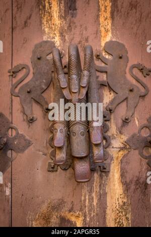 Rustico sguardo arrugginito medievale porta knocker due leoni che tiene un drago con 6 teste su un vecchio cancello casa in Albarracin Spagna Foto Stock