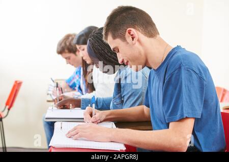 Studenti che scrivono in classe in una scuola superiore Foto Stock