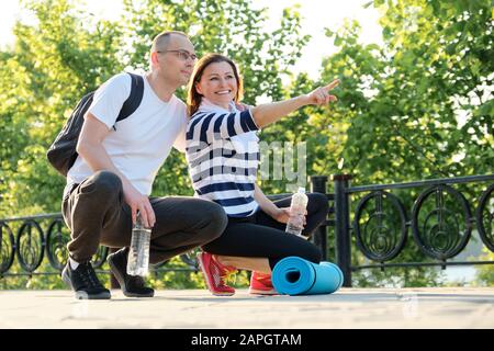 Felice coppia matura sorridente seduto nel parco, parlando di riposo dopo aver fatto sport Foto Stock