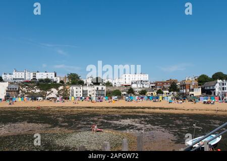 Le persone che si crogiolano al sole sulla spiaggia e le barche da diporto e da pesca nel porto di Viking Bay, Broadstairs, Kent, Regno Unito Foto Stock