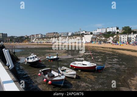 Le persone che si crogiolano al sole sulla spiaggia e le barche da diporto e da pesca nel porto di Viking Bay, Broadstairs, Kent, Regno Unito Foto Stock