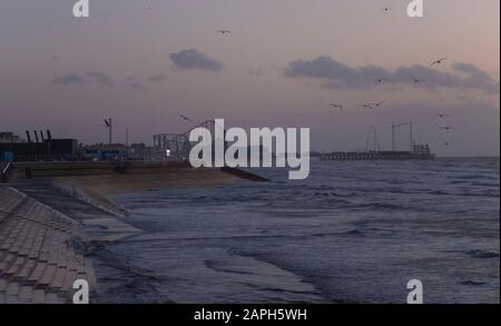 Paesaggio girato del lungomare di Blackpool mentre la marea sta uscendo, guardando verso South Pier, al tramonto Foto Stock