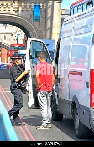 City of London donna poliziotto in uniforme parlando con uomini occupanti di furgone bianco si è fermato in strada sul Tower Bridge Southwark Londra Inghilterra UK Foto Stock