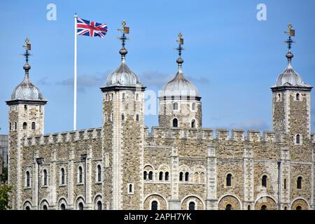 Primo piano di muro di pietra e torretta del tetto del famoso edificio storico della Torre Bianca nella Torre del castello di Londra Union Jack bandiera e meteo bandera Inghilterra UK Foto Stock