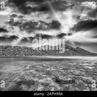 Bellissima isola con nuvole e acque cristalline al tramonto Foto Stock