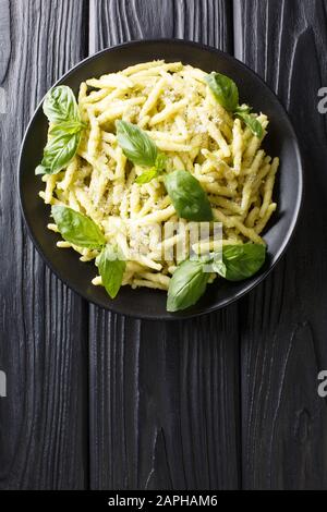 Pasta trofie preparata di fresco con pesto di basilico e parmigiano da vicino in un piatto sul tavolo. Vista dall'alto verticale Foto Stock