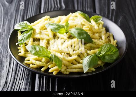 Trofie ligure cucinate con pesto di basilico e parmigiano da vicino in un piatto sul tavolo. Orizzontale Foto Stock