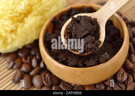 Maschera facciale per la pulizia del caffè fatta in casa in recipiente di legno con cucchiaio sui chicchi di caffè Foto Stock