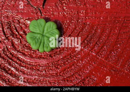 La foto mostra il fortunato trifoglio su uno sfondo rosso di legno Foto Stock