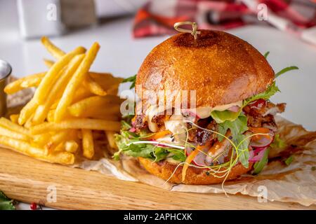 Hamburger vegetariano fresco con funghi e verdure, servito con patatine fritte su una tavola di legno, sano fast food Foto Stock