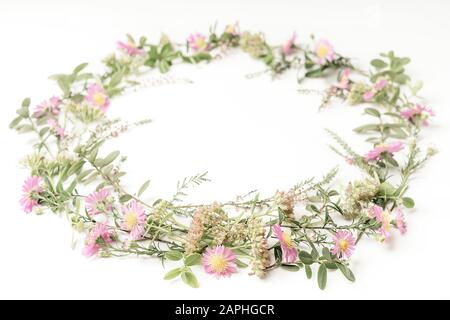 Bella gara e corona telaio con fiori di colore rosa, Heath, rami e foglie su sfondo bianco. Vista dall'alto. Copia dello spazio. Foto Stock