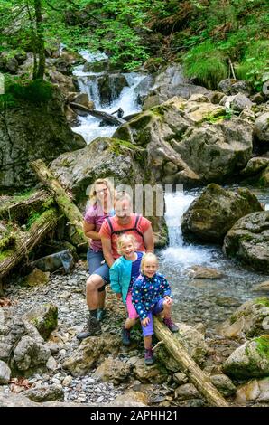 Junge Familie mit kleinen Kindern beim Wandern in den Bergen Foto Stock