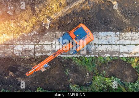 Escavatore su caterpilastrini nella fossa di fondazione durante la costruzione della fondazione dell'edificio, scavo. Vista dall'alto dell'antenna Foto Stock