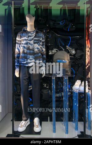 Firenze, Italia - 2020, 19 gennaio: Abbigliamento, scarpe, borsa e accessori in una boutique di moda Giorgio Armani. Paesaggio urbano riflesso nelle finestre. Foto Stock