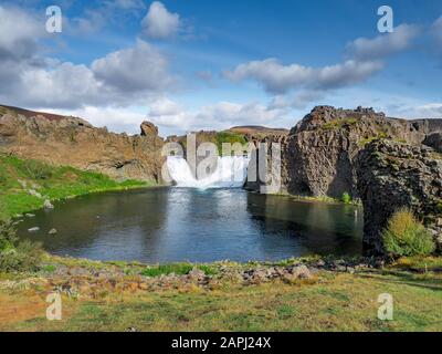 Epica vista aerea dei droni che volano su un paesaggio di cascata Hjalparfoss e laguna in una giornata di sole. Foto Stock