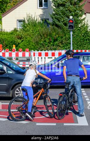 Due ciclisti in attesa su una pista ciclabile segnata perfetta a un bivio Foto Stock