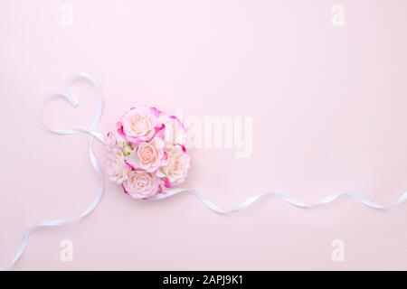 Struttura di rose rosa e cuore di nastro. Concetto di molla, disposizione piatta, spazio di copia. Composizione fiori di rosa per San Valentino, matrimonio, giorno delle donne, compleanno Foto Stock