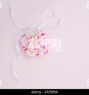 Struttura di rose rosa e cuore di nastro. Concetto di molla, disposizione piatta, spazio di copia. Composizione fiori di rosa per San Valentino, matrimonio, giorno delle donne, compleanno Foto Stock