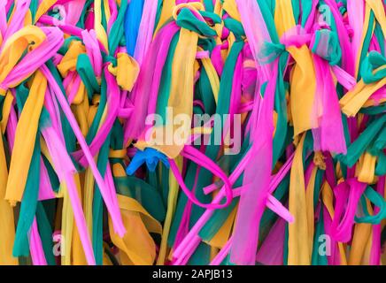 Colorato tessuto di stile tailandese che legato intorno al grande albero nel tempio per credere al popolo tailandese. Foto Stock
