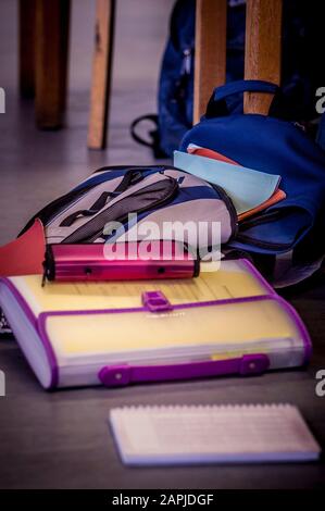 Lo zaino e i libri scolastici degli studenti sono a terra accanto alla scrivania in classe Foto Stock