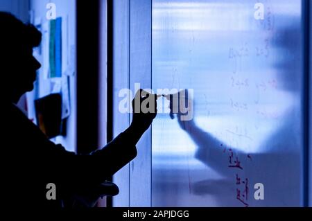 Silhouette di insegnante che scrive su lavagna bianca in classe Foto Stock