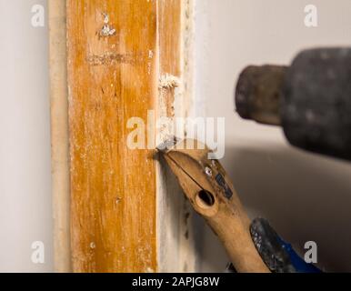 Dettaglio della rimozione della vecchia vernice bianca dal telaio della porta con pistola termica e raschietto Foto Stock