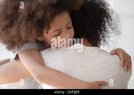 La figlia africana abbraccia la vista posteriore posteriore posteriore della madre del closeup Foto Stock