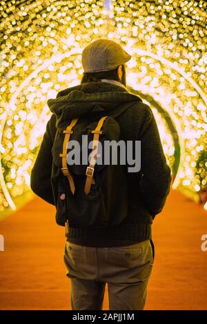 Uomo visto da dietro con luci di natale sullo sfondo Foto Stock