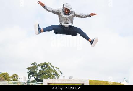 Ritratto di un uomo sportivo che salta e fa esercizio all'aperto. Sport, fitness e stile di vita sano. Foto Stock