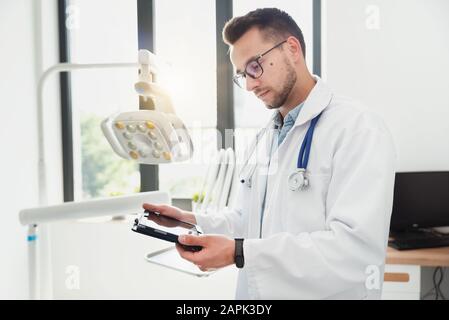 Medico utilizzando computer tablet nel suo ufficio. Moderna clinica medica Foto Stock