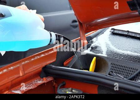 Concetto di manutenzione dell'automobile. Rifornimento di liquido lavacristalli blu in auto in inverno. Primo piano. Foto Stock