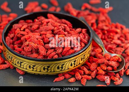 Bacche di goji in tazza d'oro in primo piano. Messa a fuoco selettiva Foto Stock