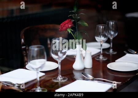 Rosa rossa in vaso di porcellana bianca su un tavolo servito in un ristorante Foto Stock