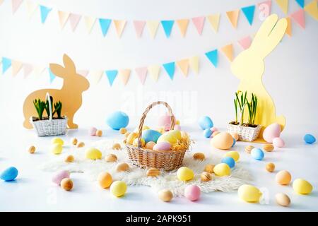 Pasqua. Molte uova di Pasqua colorate con coniglietti e cestini. Decorazione pasquale della camera, sala giochi per bambini. Cesto con carote e conigli. Foto di Pasqua. Nido, uova, scatole di fieno. Foto Stock