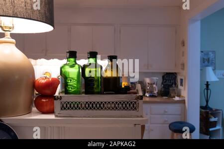 Bottiglie di vetro di olio di oliva sano allineate su un ripiano domestico in cucina Foto Stock