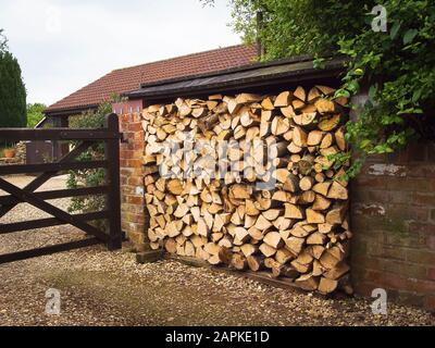 Un mucchio ordinato di tronchi tagliati accatastati di legno in attesa di essere usato come combustibile in un fuoco che brucia il legno nel Regno Unito Foto Stock