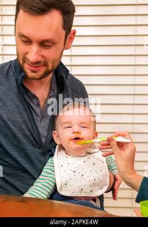 Genitori cucchiaio di alimentazione bambino di sette mesi Foto Stock