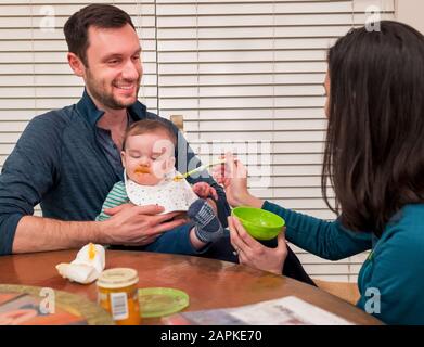 Genitori cucchiaio di alimentazione bambino di sette mesi Foto Stock