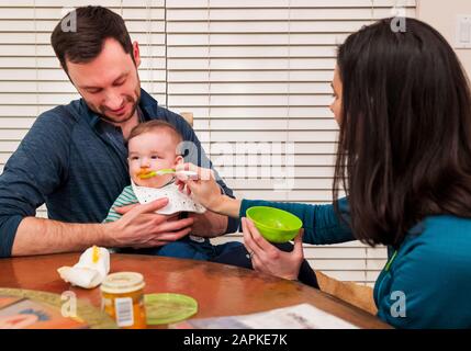 Genitori cucchiaio di alimentazione bambino di sette mesi Foto Stock