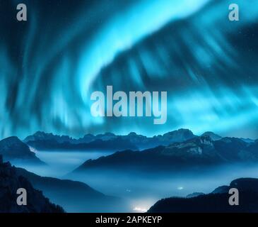 Aurora borealis sopra le montagne in nebbia di notte Foto Stock